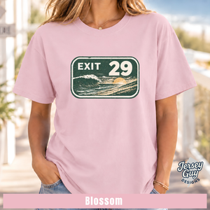 A woman wearing a light pink t-shirt with a retro 'EXIT 29' wave graphic on the chest. The image has a 'Jersey Guy Designs' logo in the bottom right corner and a pink banner at the bottom labeled 'Blossom'.
